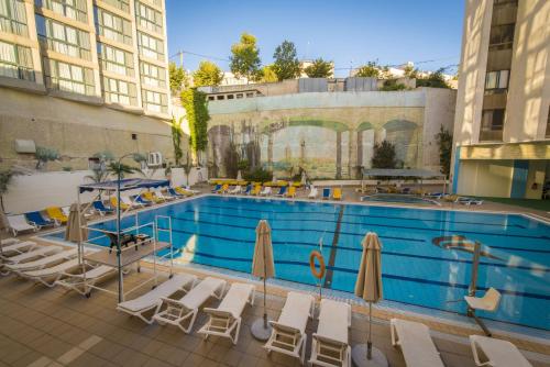 a large swimming pool with chairs and umbrellas at Shalom Jerusalem Hotel in Jerusalem