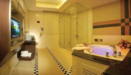 a bathroom with a tub and a tv and a shower at Spring Breeze Boutique Motel in Kaohsiung