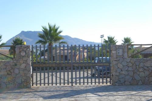 a gate with a bench behind a stone fence at Casa Vacanze Libeccio - Villetta con giardino e piscina condominiale in Custonaci