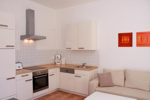 a kitchen with white cabinets and a sink and a couch at Villa Elise in Bad Schandau