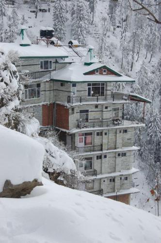 a building covered in snow with snow covered trees at Hotel Snowflake in Nārkanda