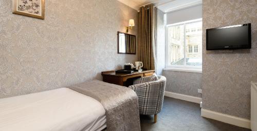 a hotel room with a bed and a television at The Atholl Palace in Pitlochry