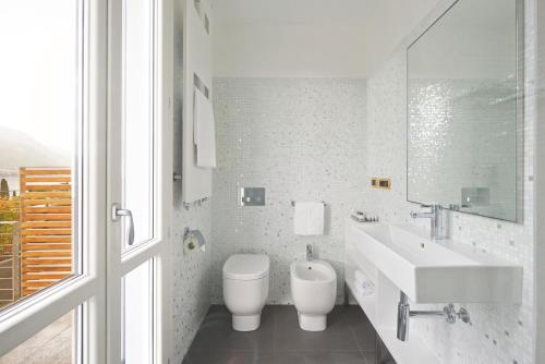 a white bathroom with a sink and a toilet at Hotel Belvedere in Bellagio