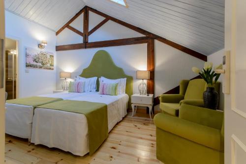 Villa Rio Guest House Suites في بورتيماو: غرفة نوم بسرير كبير واريكة خضراء