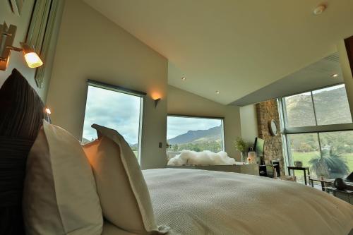 a bedroom with a large bed with pillows and windows at Bushland in Halls Gap