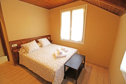 a bedroom with a bed with a window and a chair at Apartamentos SNÖ Mont Romies in Salardú