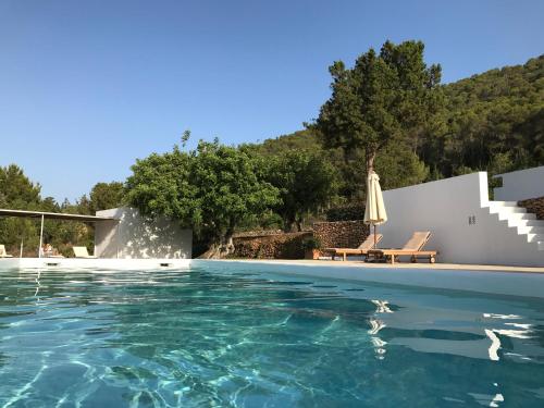 a pool with an umbrella and a chair and an umbrella at Can Poeta in Sant Carles de Peralta