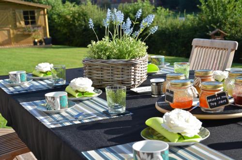 a table with plates of food and a basket of flowers at La Villa Belle in Belle-et-Houllefort