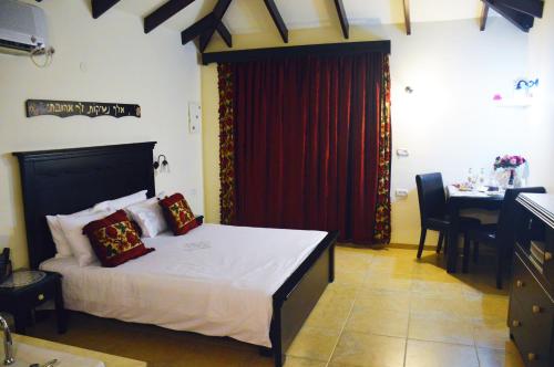 a bedroom with a bed with a red curtain and a table at Ayelet Ahavim in Livnim