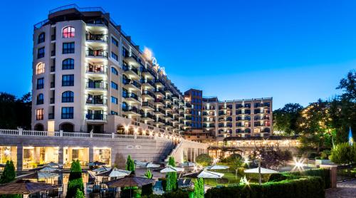 um hotel com mesas e guarda-sóis em frente a um edifício em SH Dolce Vita- All Inclusive - Free Aquapark & Beach em Golden Sands