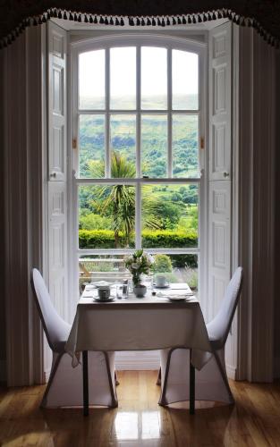 a table with chairs in front of a large window at Kilmore Country House in Glenariff