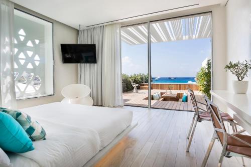 a bedroom with a bed and a view of the ocean at Mykonos Dove Beachfront Hotel in Platis Gialos