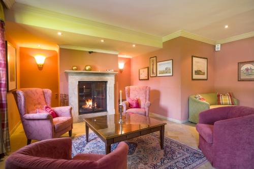 a living room with pink chairs and a fireplace at Sporthotel Austria in Sankt Johann in Tirol