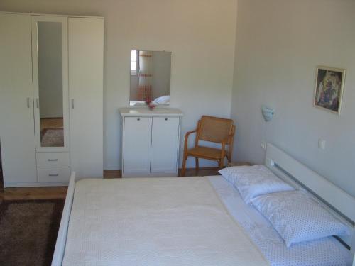 a bedroom with a bed and a chair and a mirror at Apartment Kovacic Jurlina in Poljica