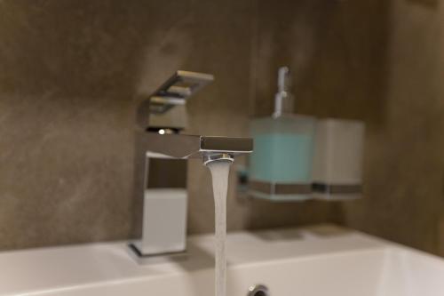 a bathroom sink with a faucet with water coming out at Villa Rose in Sarajevo