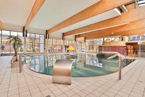 ein großer Innenpool in einem Gebäude mit Fenstern in der Unterkunft Sporthotel Kapfenberg in Kapfenberg