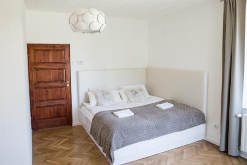 biała sypialnia z łóżkiem i drewnianą podłogą w obiekcie Apartment Nearto Old Town Na Ustroniu street w Krakowie