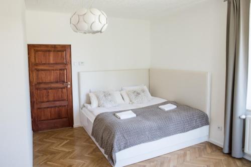 a white bedroom with a bed and a wooden floor at Apartment Nearto Old Town Na Ustroniu street in Krakow