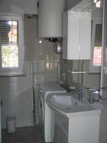 a bathroom with a sink and a washing machine at Apartment Kovacic Jurlina in Poljica