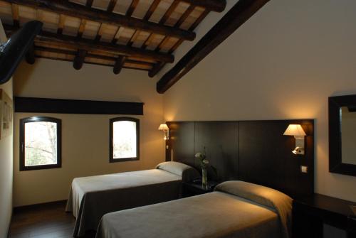 a hotel room with two beds and two windows at Molí Blanc Hotel in Jorba