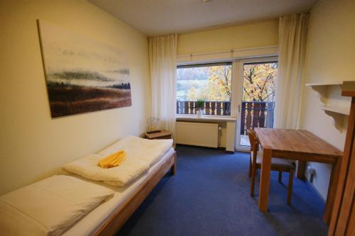 Zimmer mit einem Bett, einem Tisch und einem Fenster in der Unterkunft Seminarhaus am Liebfrauenberg in Haintchen