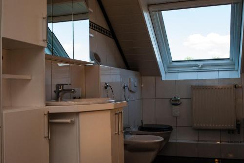 een badkamer met een wastafel, een toilet en een raam bij Ferienwohnung Wolf in Greven