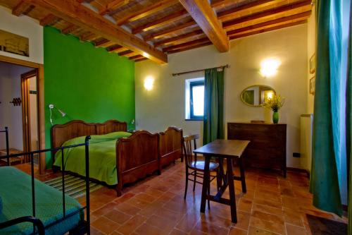 グッビオにあるAgriturismo Foglieの緑の壁のベッドルーム(テーブル、椅子付)