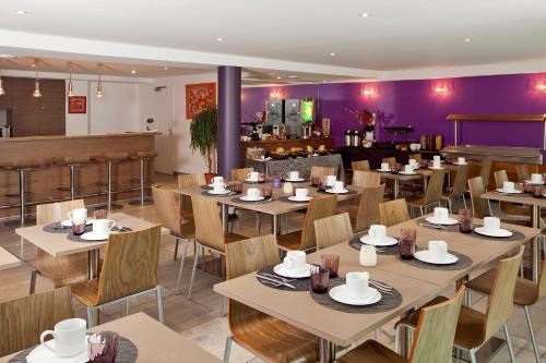 um restaurante com mesas e cadeiras e paredes roxas em Residhome Metz Lorraine em Metz