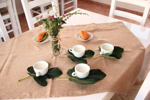 a table with white cups and plates of food on it at Villa Giulia&Gaia - Guest House in Nardò