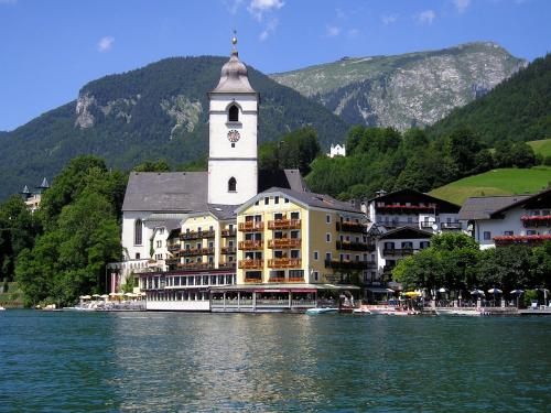 a building with a clock tower next to a body of water at Pension Waldhof in Koppl