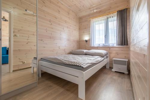 1 dormitorio con 1 cama en una pared de madera en Amelia, en Krynica Morska