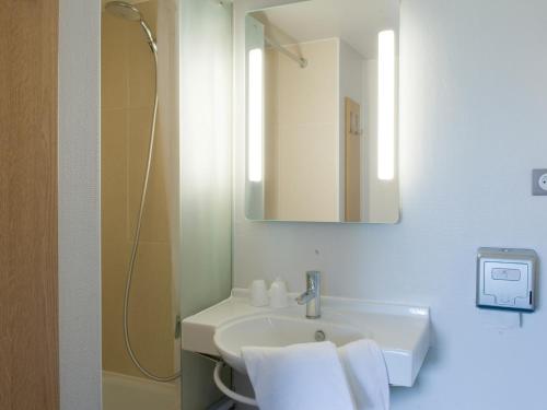 a white bathroom with a sink and a mirror at B&B HOTEL Amiens in Longueau