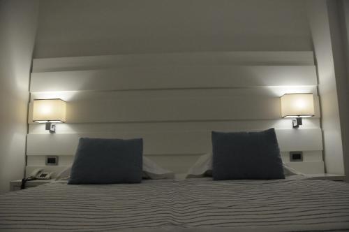 a bed with two pillows and two lights on it at Sunshine Club Hotel Centro Benessere in Ricadi