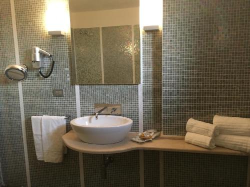 ein Badezimmer mit einem Waschbecken, einem Spiegel und Handtüchern in der Unterkunft Hotel Langhe & Monferrato in Costigliole dʼAsti