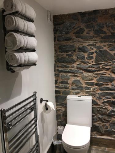a bathroom with a white toilet and a stone wall at Riverside Suites Llangollen in Llangollen