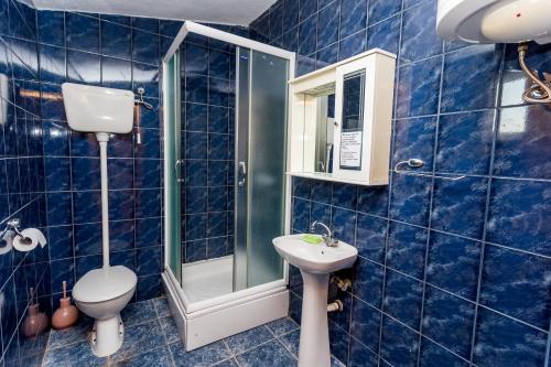 a blue tiled bathroom with a toilet and a sink at Luštica Apartments in Lustica