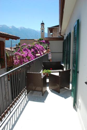 un balcone con tavoli, sedie e fiori viola di Casa Fanny a Limone sul Garda