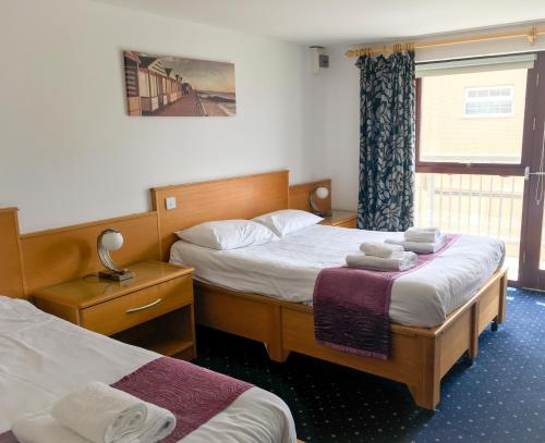 una camera d'albergo con due letti e una finestra di The Beach Motel a Trearddur