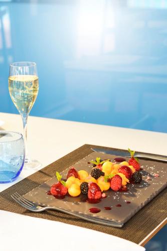 a plate of fruit on a table with a glass of wine at Ibis Jerez De La Frontera Cadiz in Jerez de la Frontera