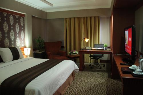 a hotel room with a bed and a desk at Abadi Suite Hotel & Tower in Jambi
