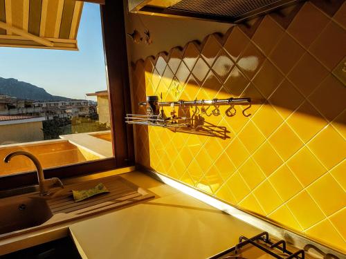 cocina amarilla con fregadero y ventana en La Casa di Chris, en Golfo Aranci