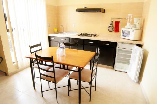 uma cozinha com uma mesa de madeira e algumas cadeiras em Hotel y Suites El Refugio de Don Carlos em Zacatecas