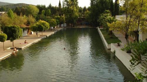 a body of water with people swimming in it at Hotel Plaza Manjón in Villanueva del Arzobispo