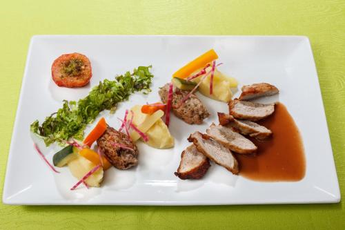 a white plate of food with meat and vegetables at Auberge Du Cheval Blanc in Baud