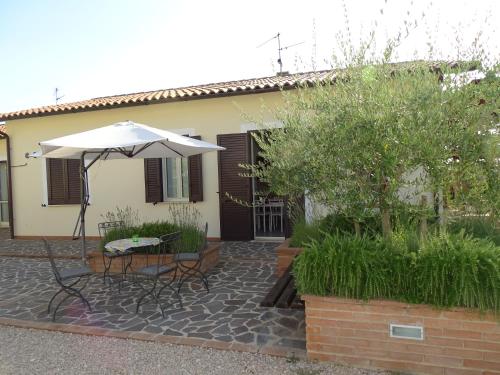a patio with a table and an umbrella in front of a house at Residence Terra Dei Santi Country House in Spello