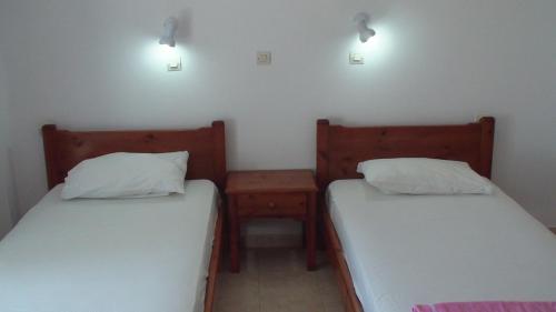 two beds in a room with two lamps on the wall at Creta Vassakis Studios in Kefalos