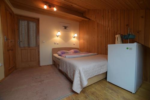 a small bedroom with a bed and a refrigerator at Inkliuzas in Nida