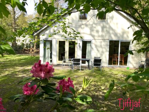 a white house with windows and pink flowers at Vakantiewoning Tjiftjaf in "Het Fonteinbos" in Oudemirdum