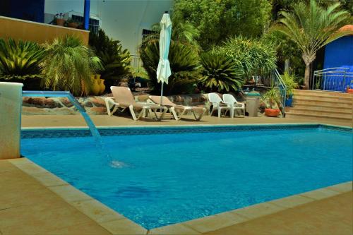 a swimming pool with an umbrella and chairs and a pool at Ayelet Ahavim in Livnim