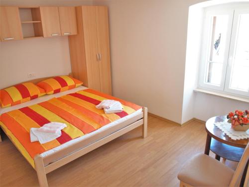 Schlafzimmer mit einem Bett, einem Tisch und einem Fenster in der Unterkunft Apartment Rado in Vrbnik